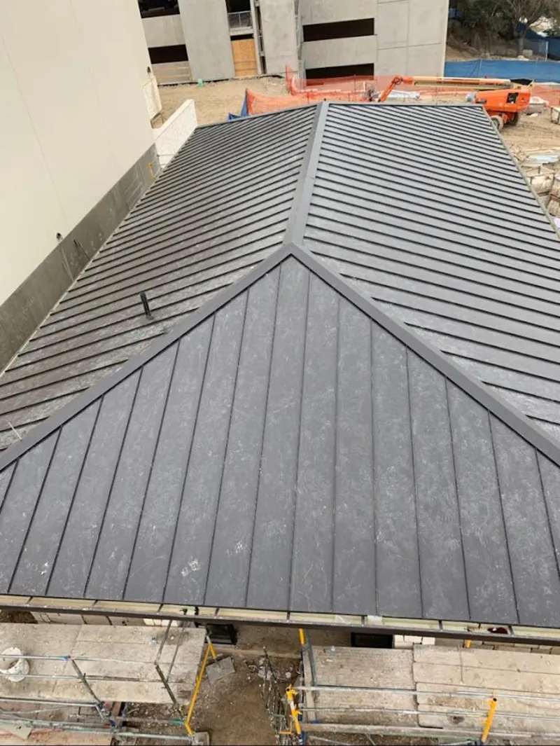 Commercial metal roof construction with crane equipment in Somers